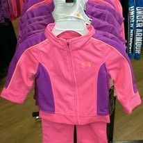 A pink and purple Under Armour zip-up track jacket on a hanger in a store.