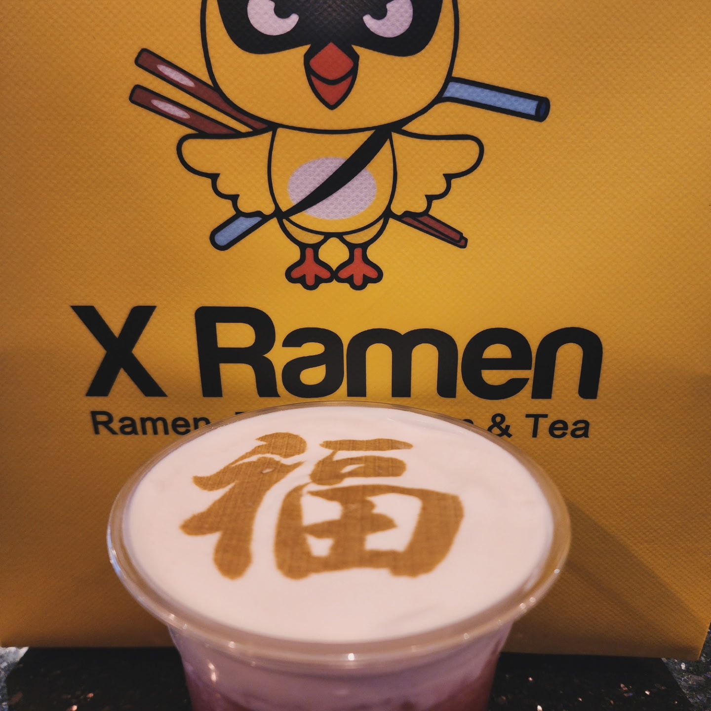 a drink with a creamy top featuring a Chinese character