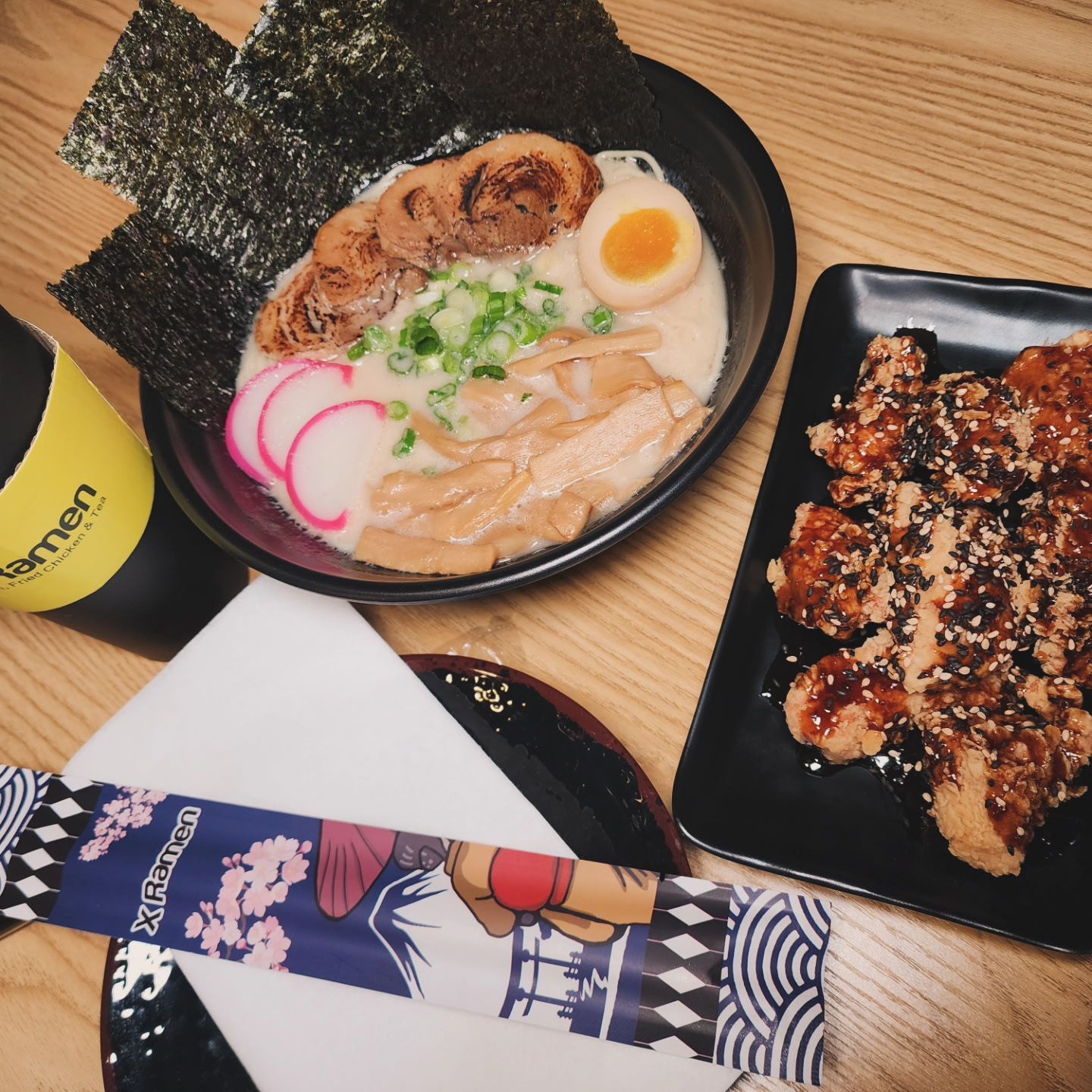 ramen bowl with pork, egg, and nori, beside fried chicken
