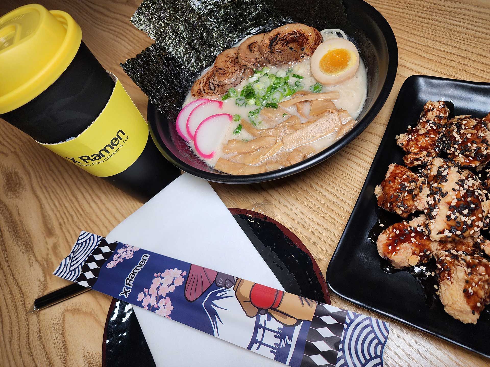 ramen bowl, fried chicken, and drink on a wooden table
