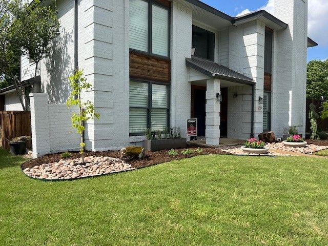 Modern two-story white house with large windows, front porch, and a green lawn landscaping.