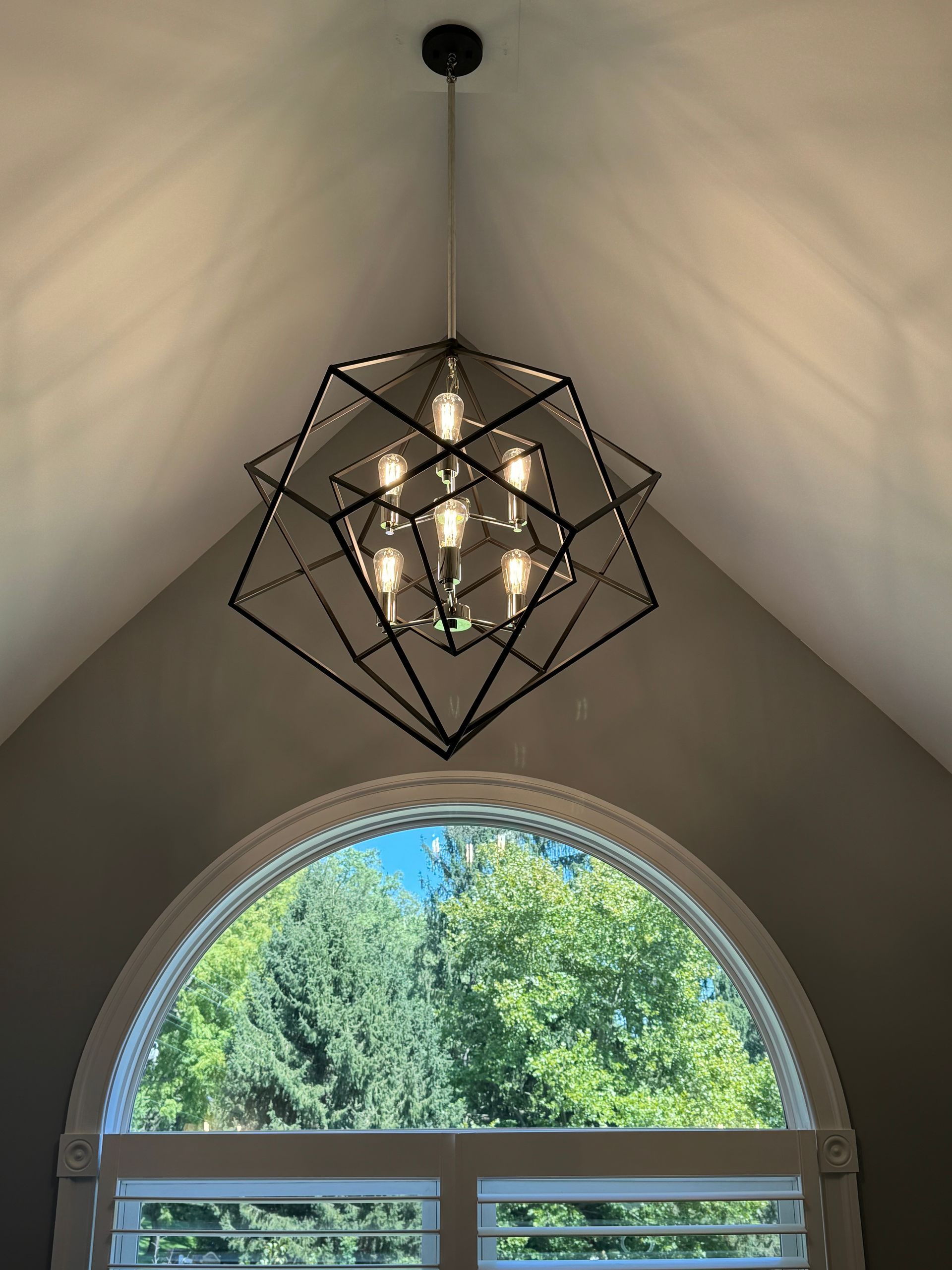 A chandelier is hanging from the ceiling above a window.