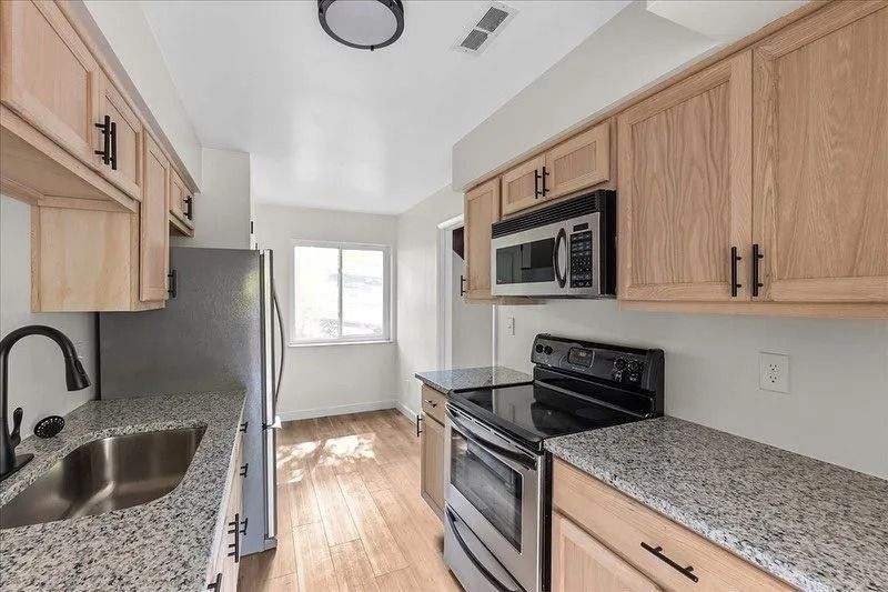 A kitchen with wood cabinets, granite countertops, and stainless steel appliances.