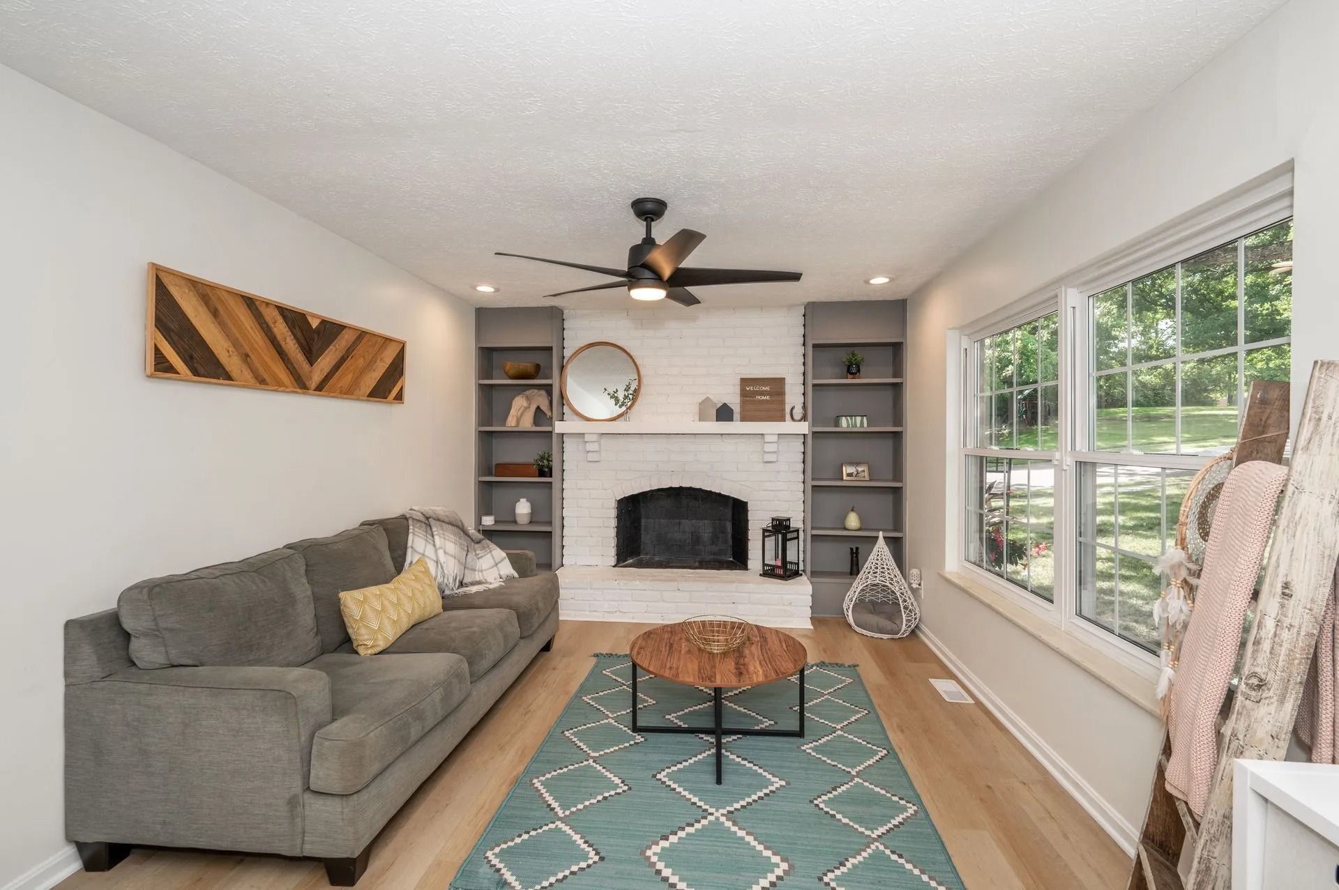 Living room with grey sofa, fireplace, and built-in shelves; wood and teal accents.