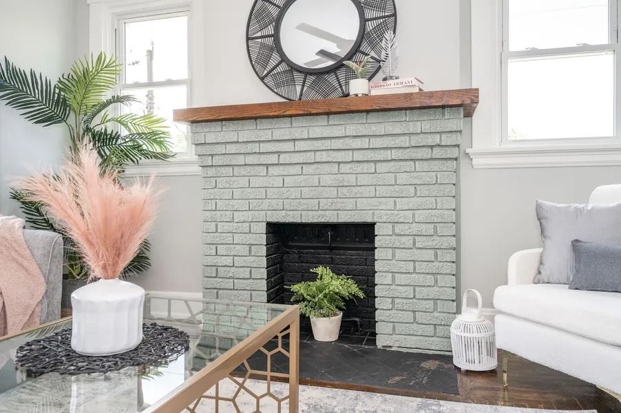 Living room with a painted brick fireplace, mirror, and plants.