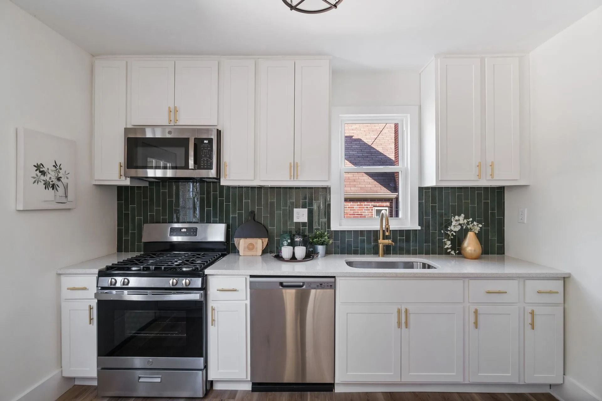 White kitchen with stainless steel appliances, green backsplash, and gold hardware.