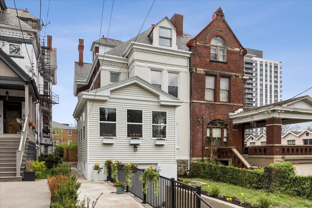 Row of houses, white and red brick, with driveways and small yards; sunny day.