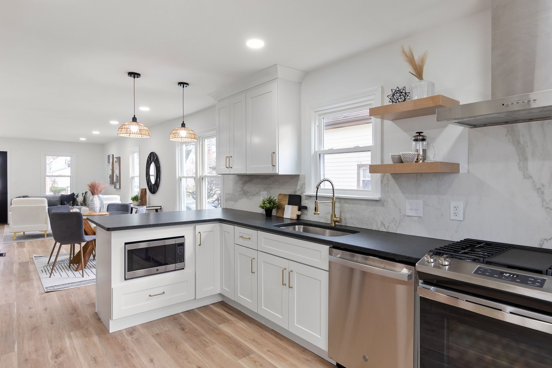 Modern kitchen with white cabinets, stainless steel appliances, and dark countertops.