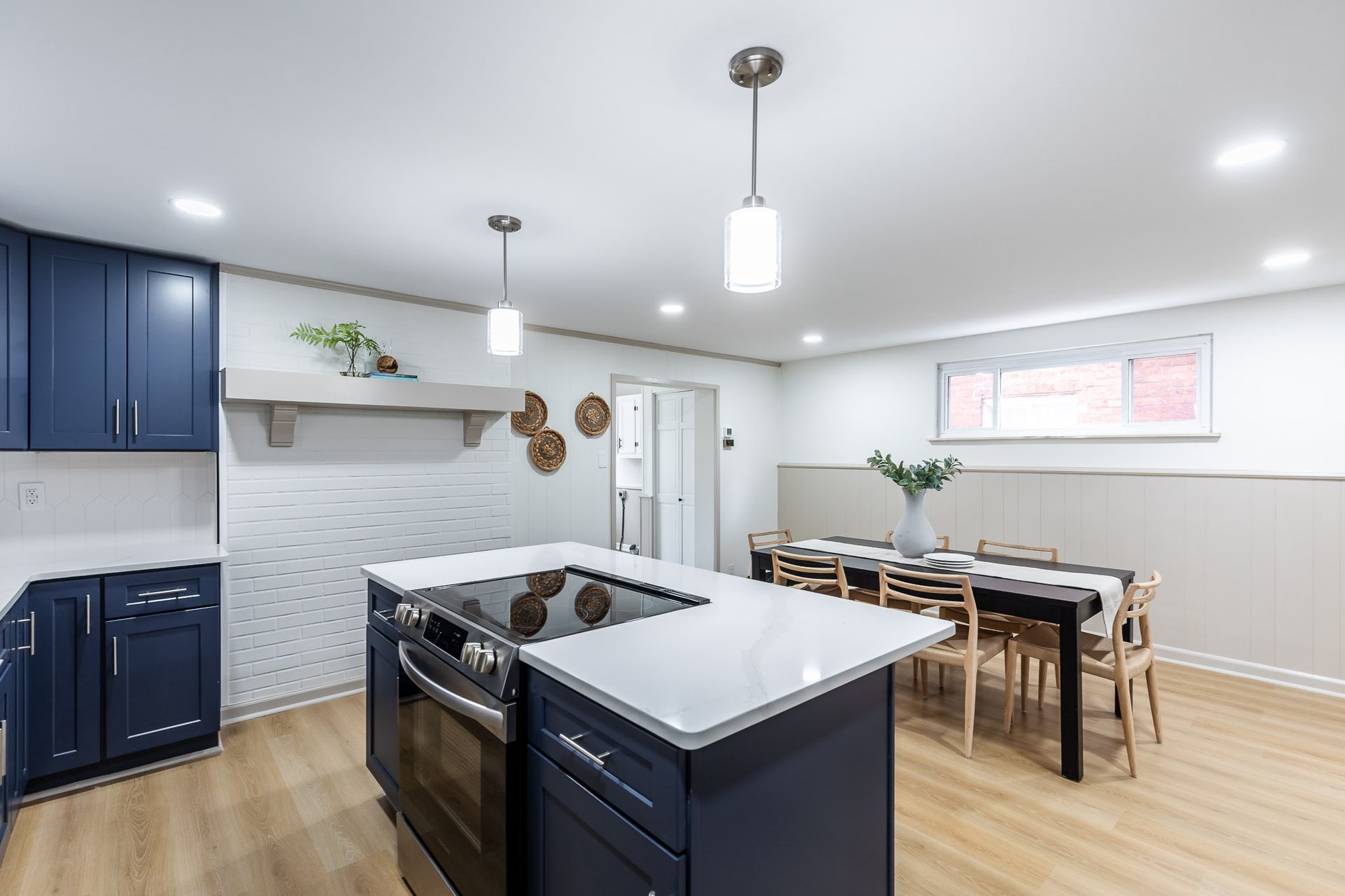Modern kitchen with navy cabinets, white countertops, and a dining area.