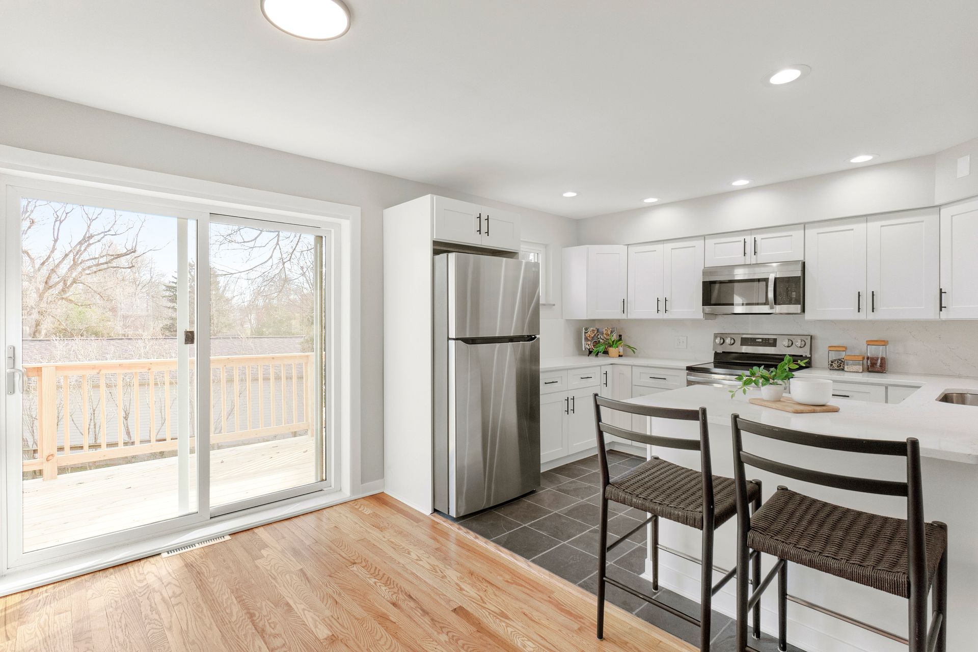 Modern kitchen with white cabinets, stainless steel appliances, and a sliding glass door to a deck.