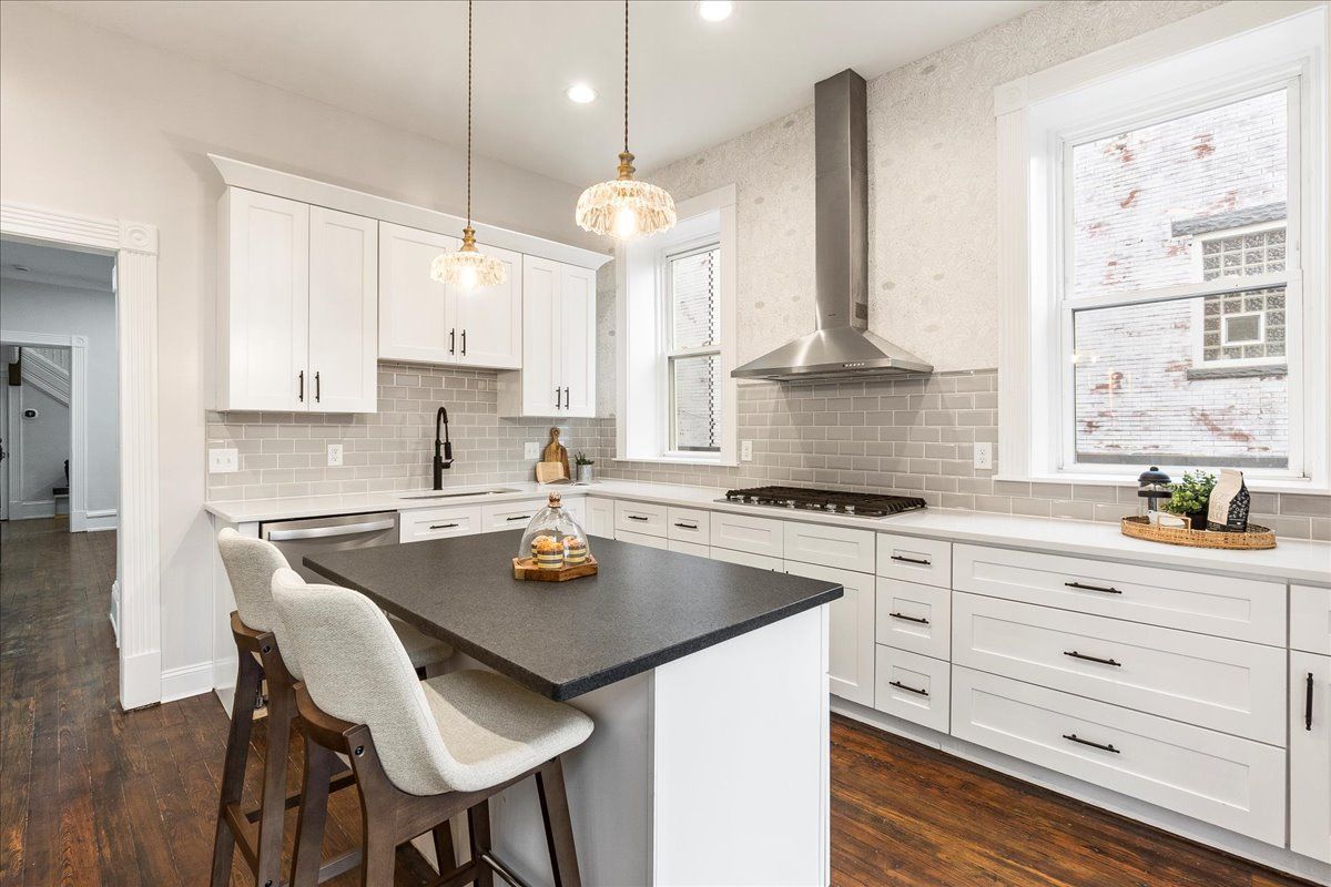 Modern white kitchen with island, dark countertop, and two bar stools.