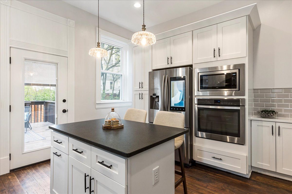 Bright white kitchen with dark island and stainless steel appliances.