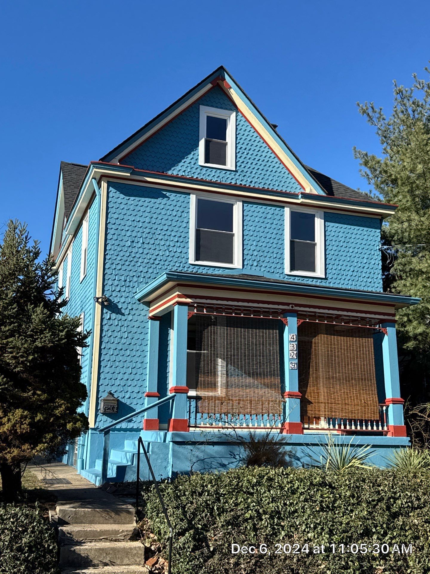 Blue two-story house with porch; blue siding, white-framed windows, against a clear blue sky.