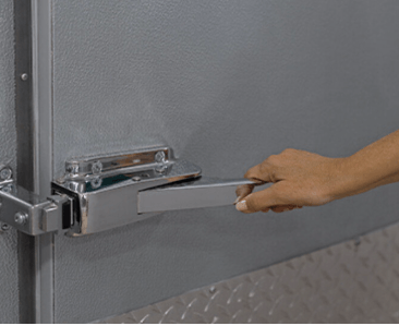 Hand pulling a chrome lever to open a gray door.