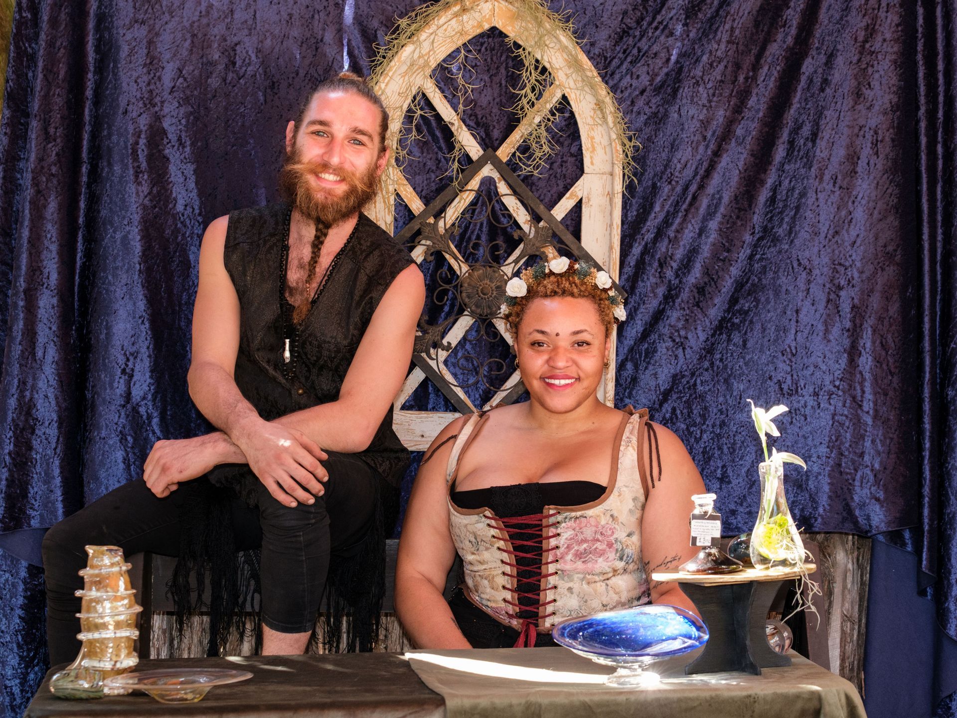 Man blowing glass at a festival; colorful palette, onlookers in background, outdoor setting.