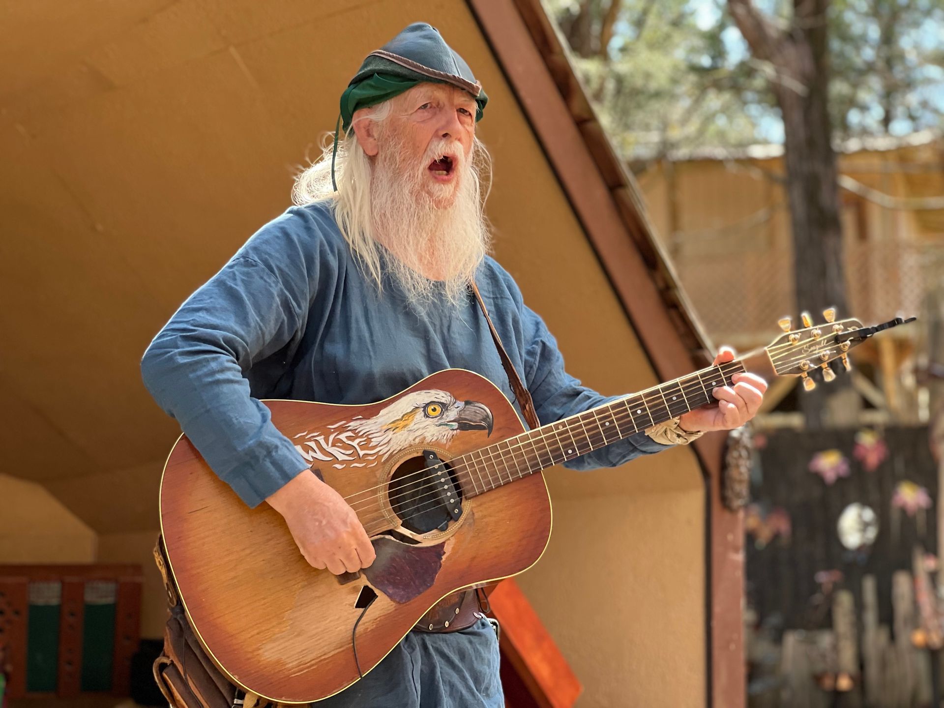 Sherwood Forest Faire logo: Four costumed figures, green and red clothing, with trees in the background. 