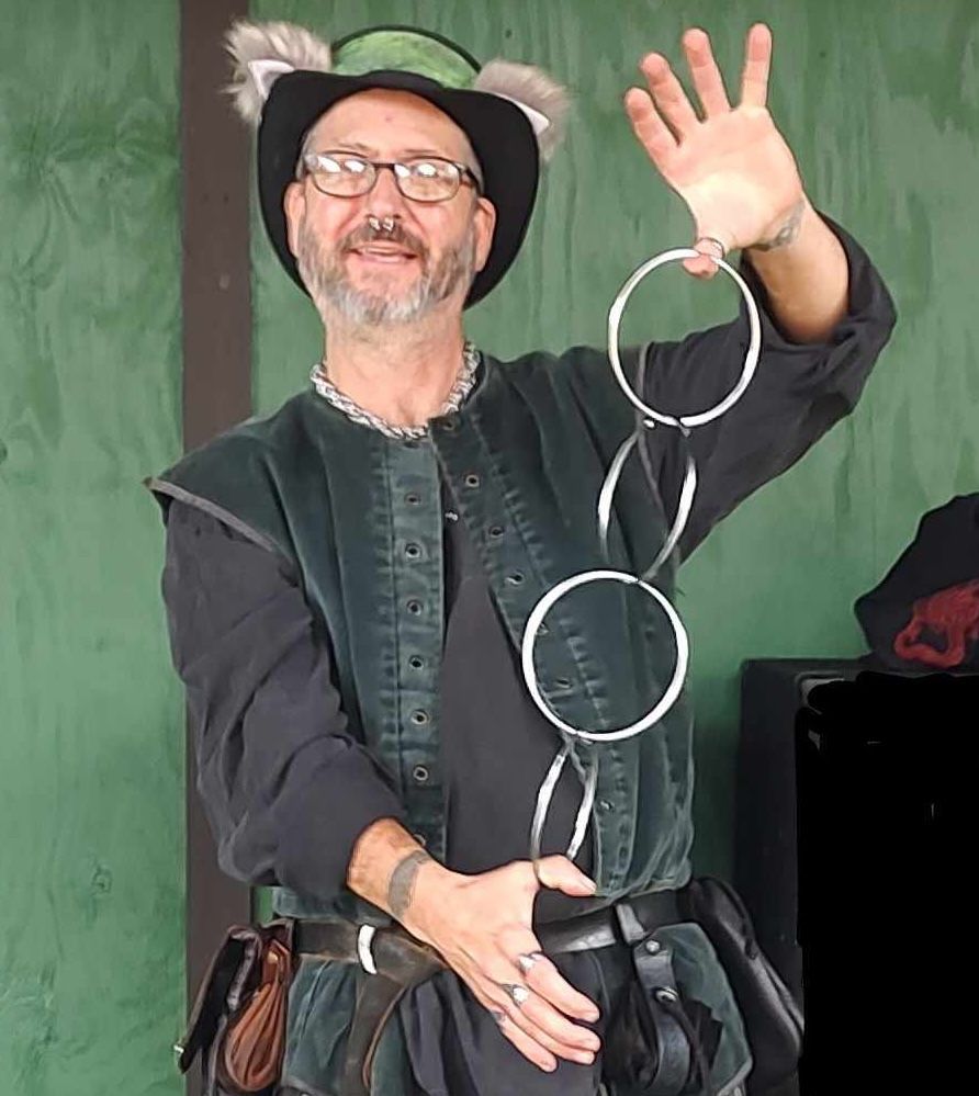 Woman with floral crown, face paint, and elf ears smiles. Man with hat and beard looks at the camera.