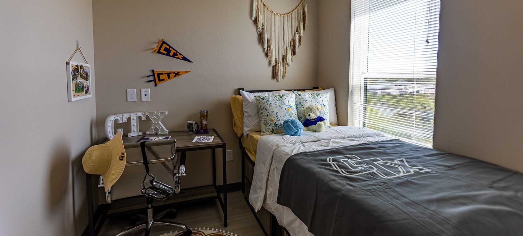 Cozy bedroom with a bed, desk, chair, wall art, and window with daylight
