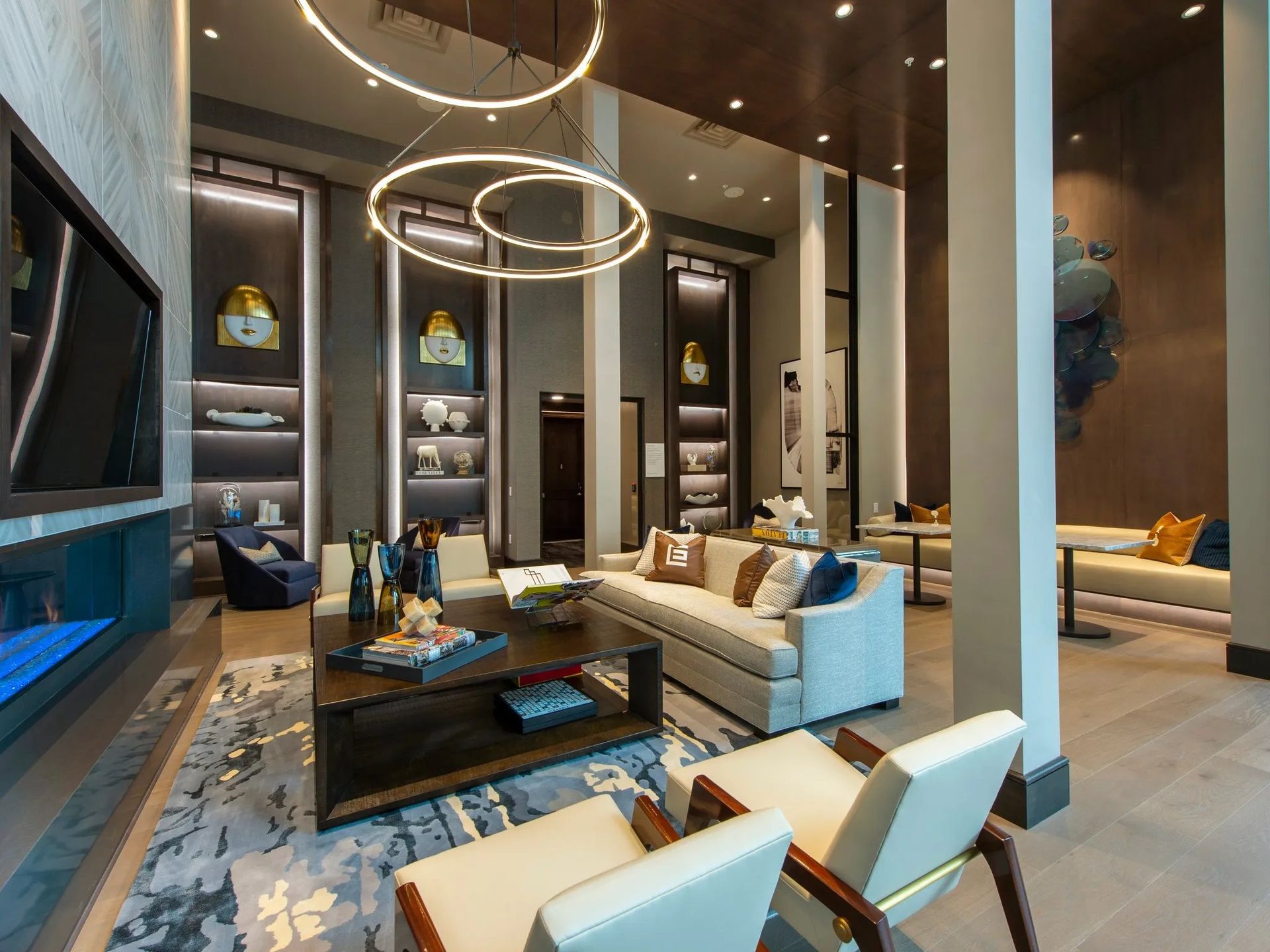 Modern luxury living room with beige sofas, dark wood accents, and large circular pendant lights
