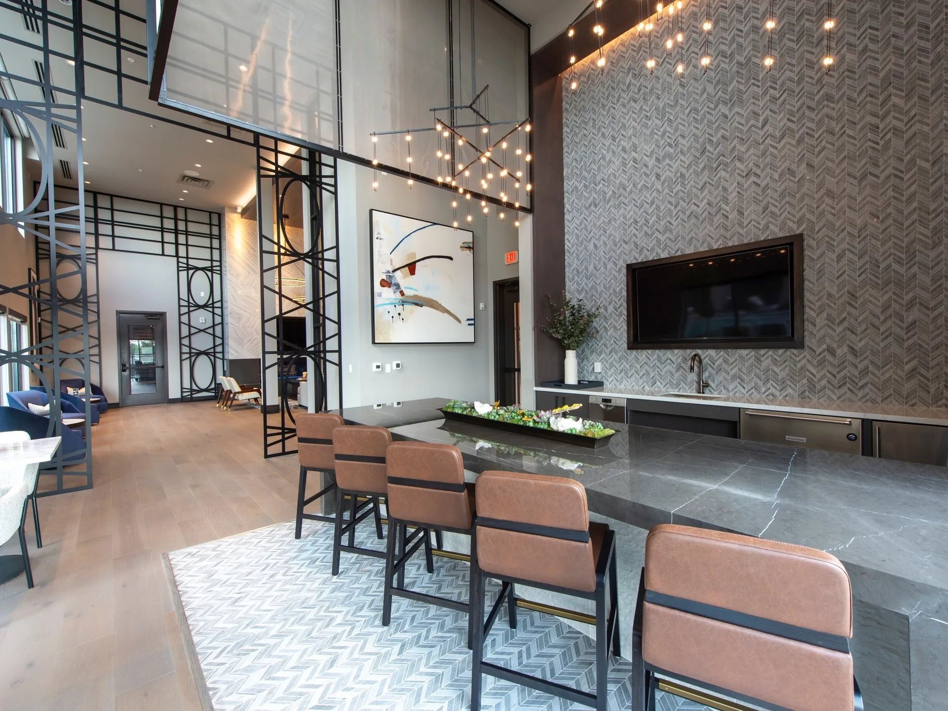 Modern lobby with high ceilings, hanging lights, fireplace, and lounge seating on a patterned rug