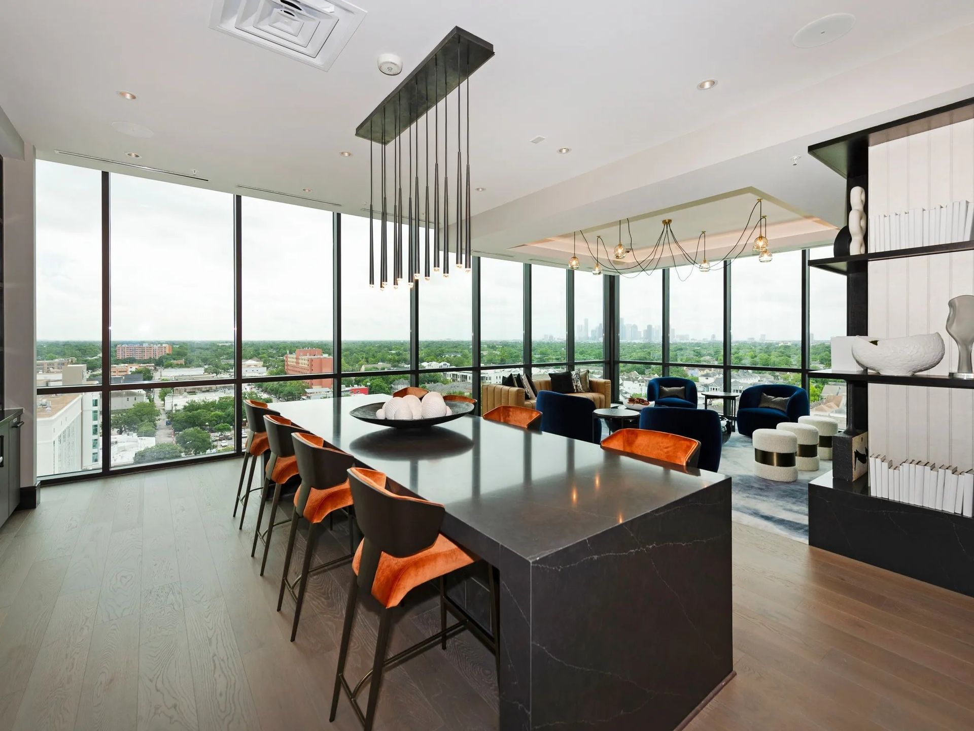 Modern open-concept kitchen and dining area with island, black chairs, floor-to-ceiling windows, and city view