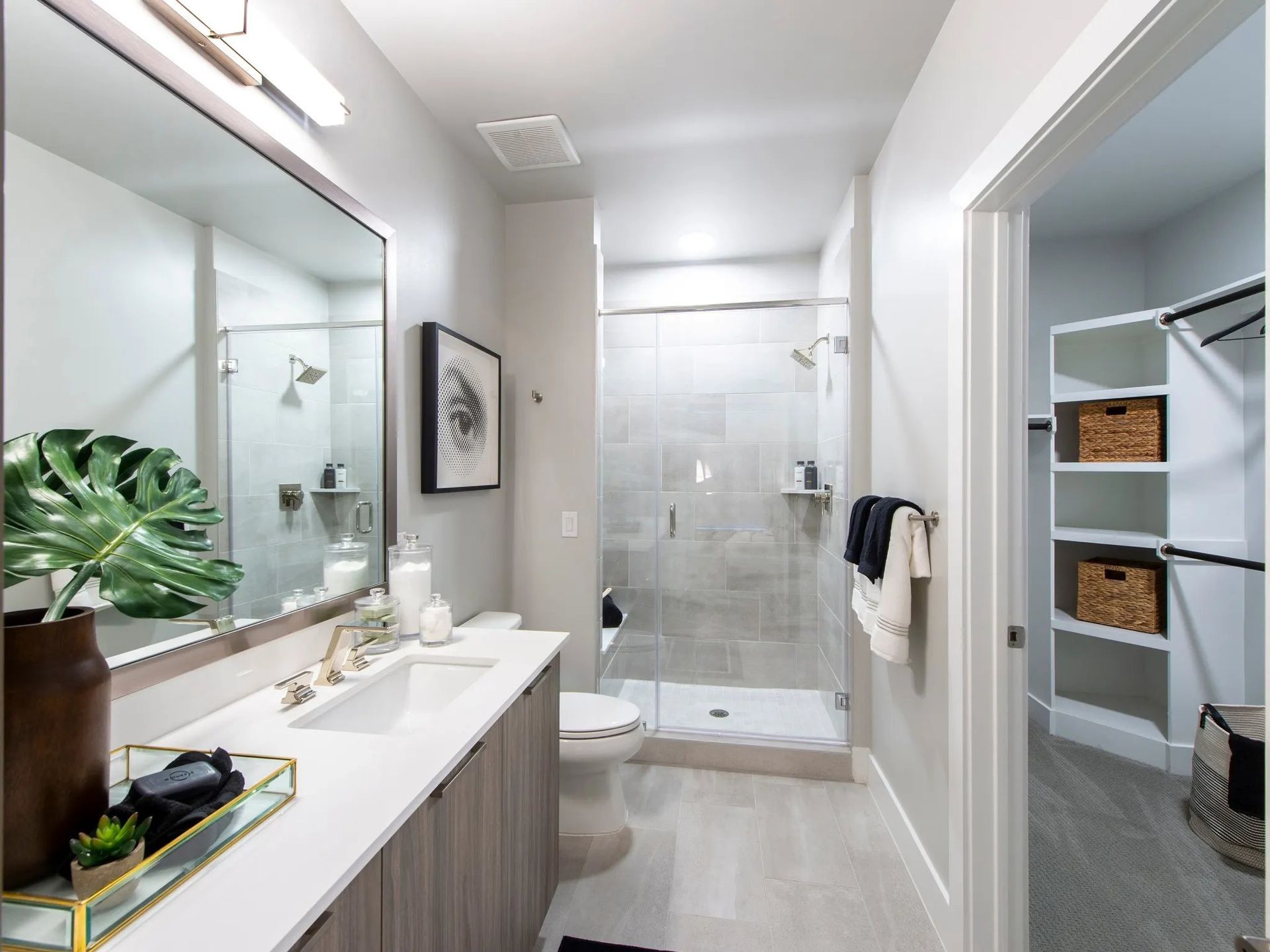 Bright modern bathroom with double vanity, glass shower, and white tile walls.