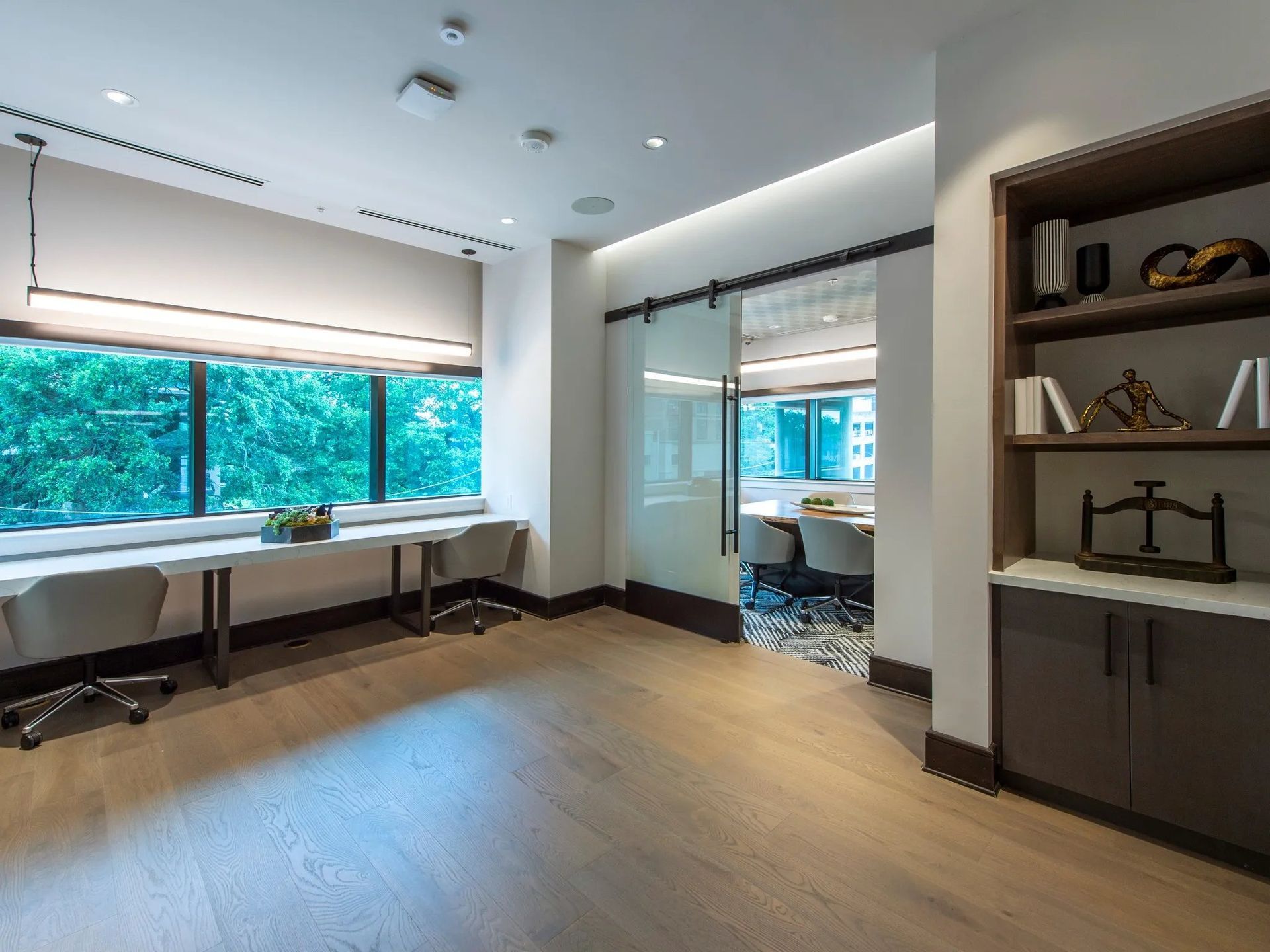 Bright modern office with desks, large windows, and built-in shelving.