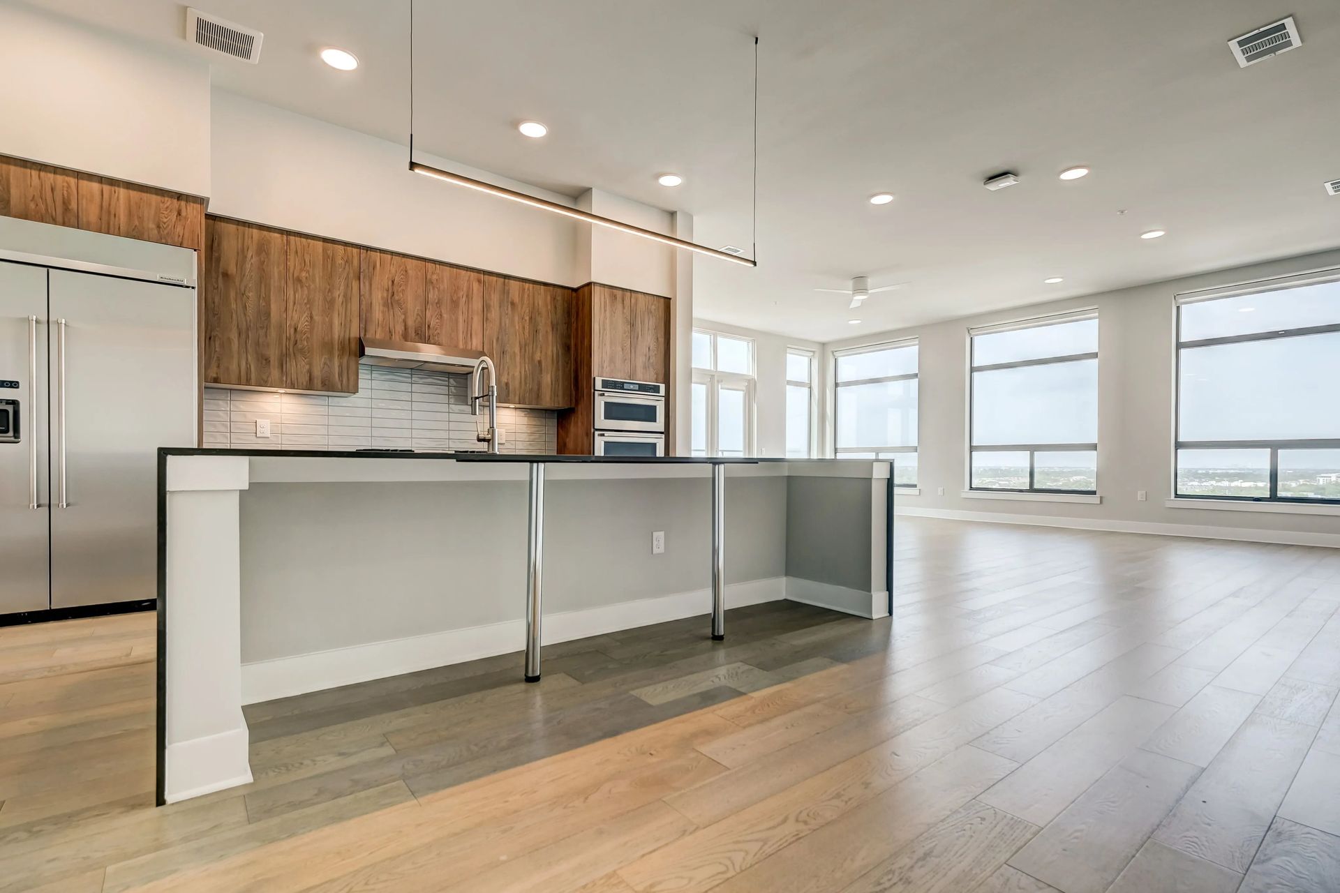 Open-concept kitchen and living area with wood cabinets, island, and large windows.
