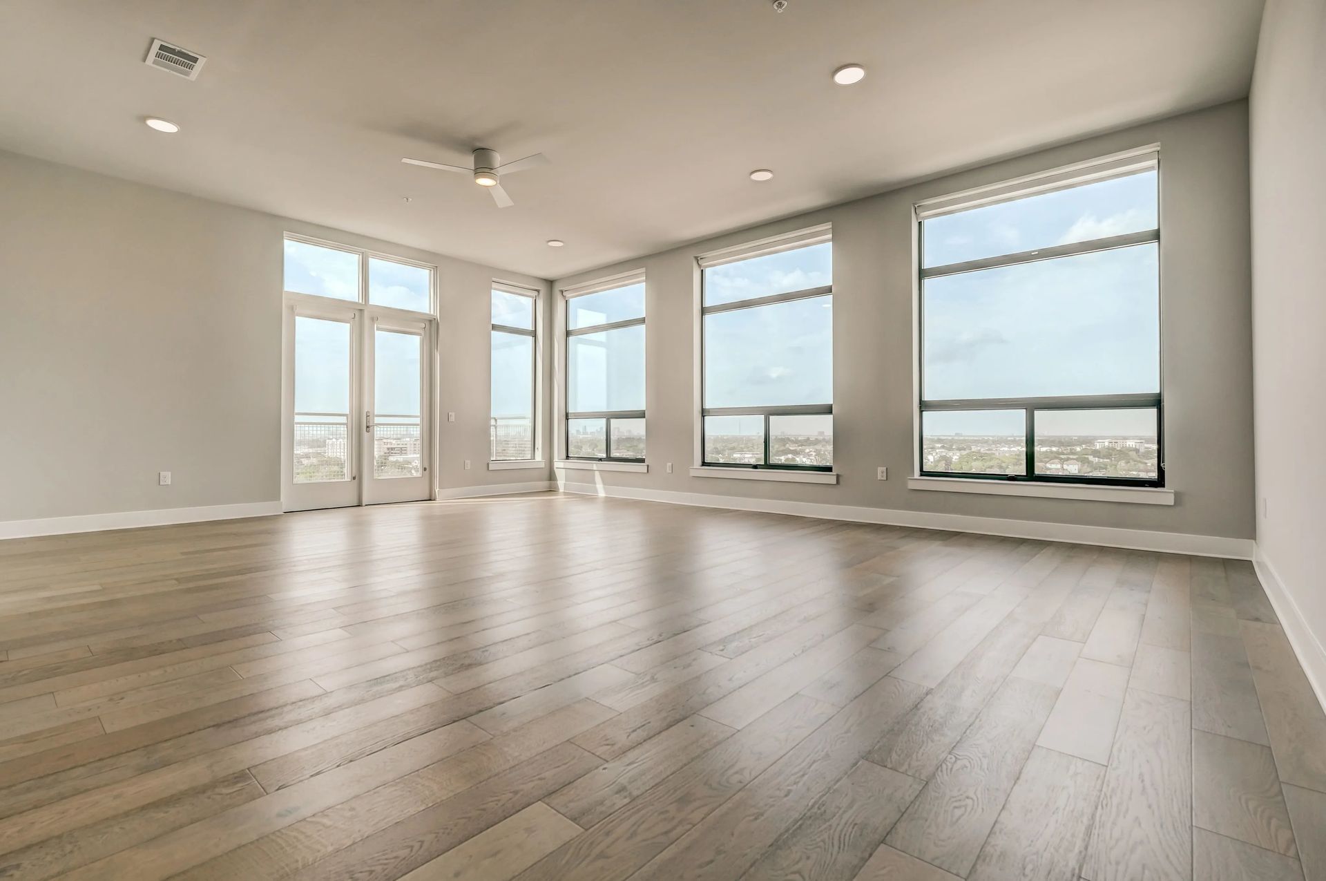 Spacious empty modern living room with large windows and light wood floors
