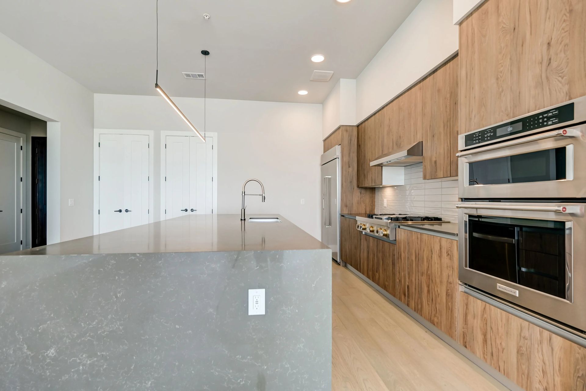 Modern kitchen with wood cabinets, large island, stainless steel appliances, and light wood flooring