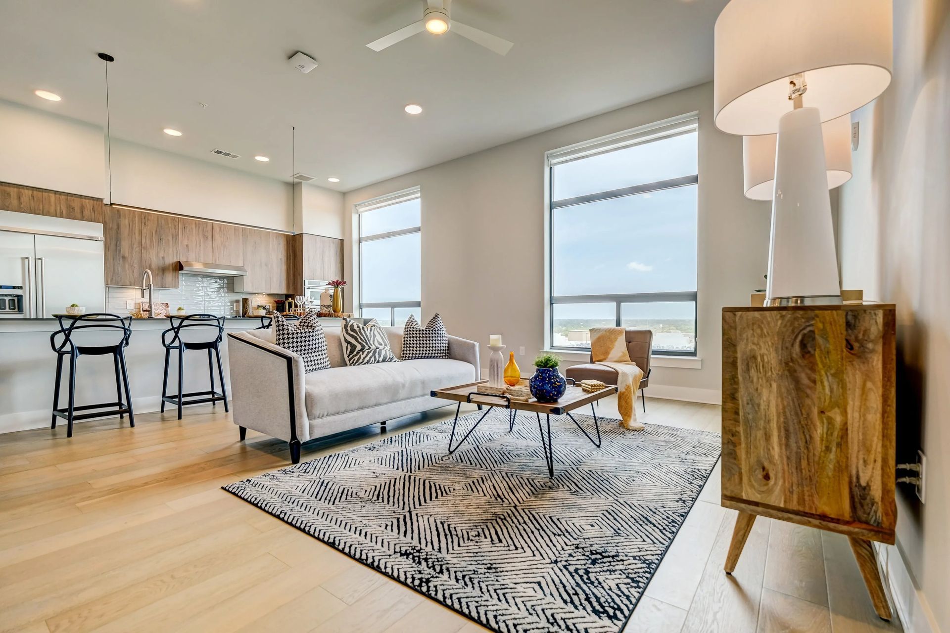 Bright modern living room with kitchen, sofa, coffee table, and large window light