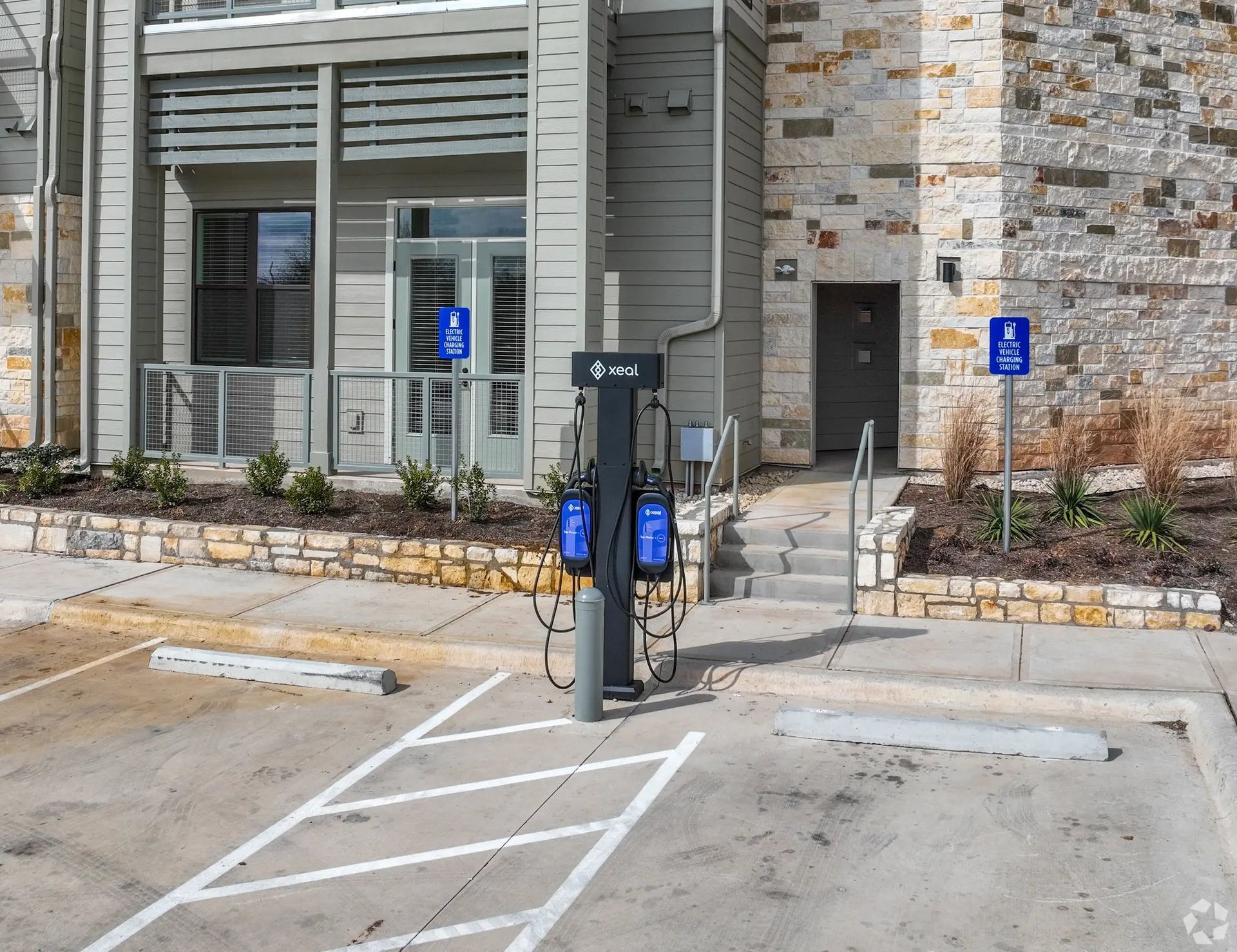 Outdoor EV charging station in a parking lot beside a building entrance