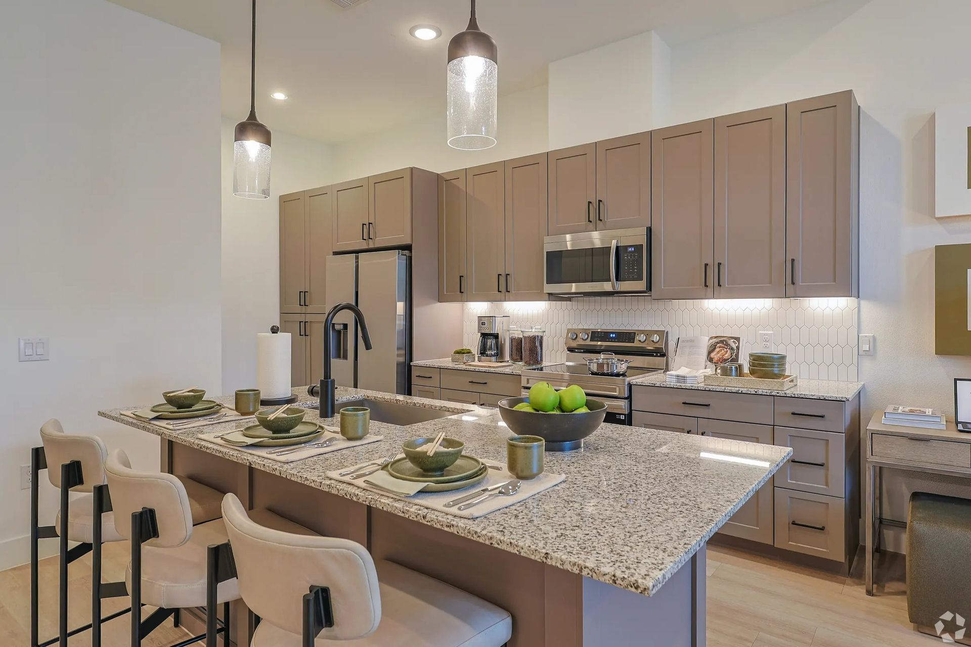 Modern kitchen with granite island, bar stools, pendant lights, and set dining table