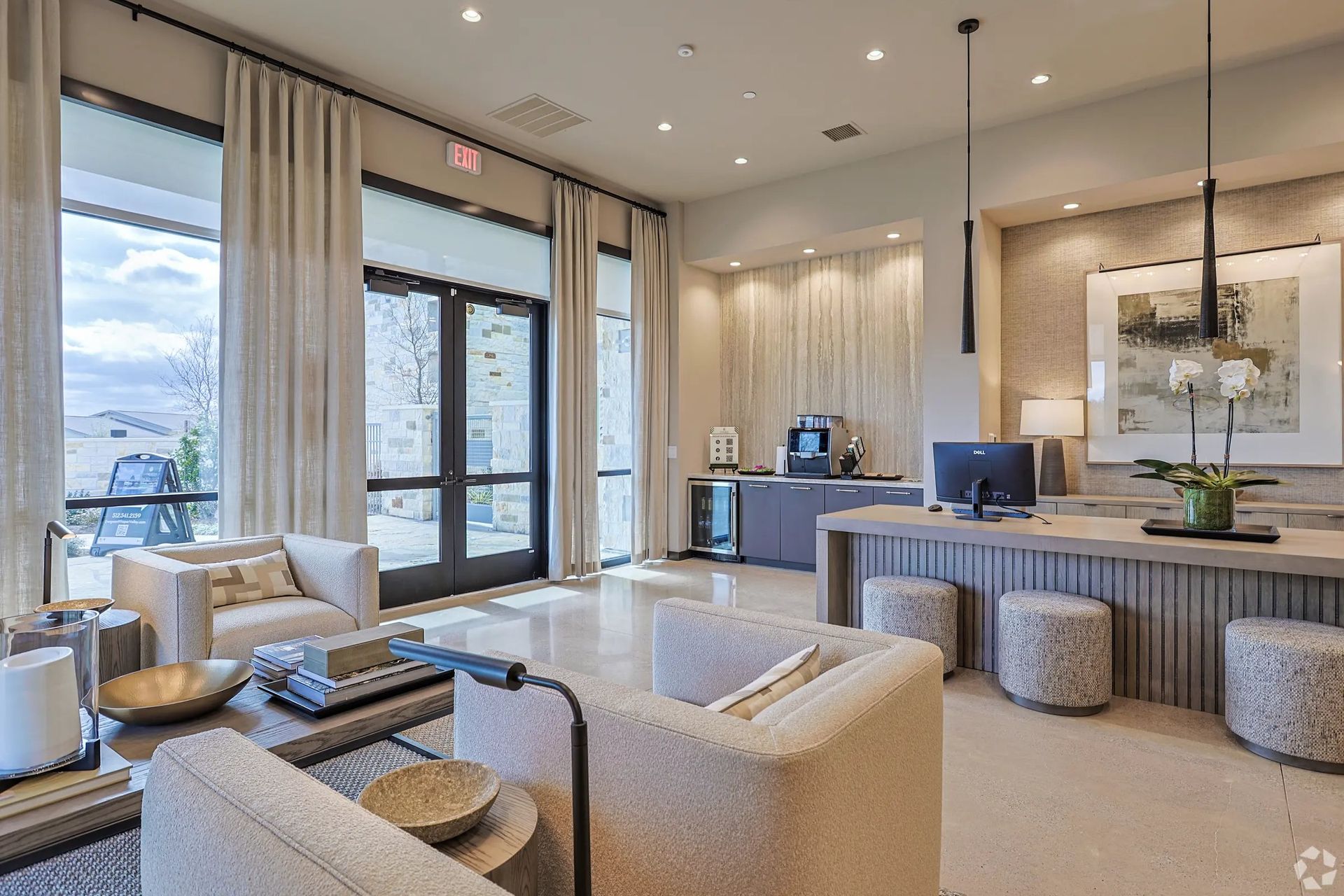 Modern living room with beige seating, large windows, and a dark wood fireplace mantel