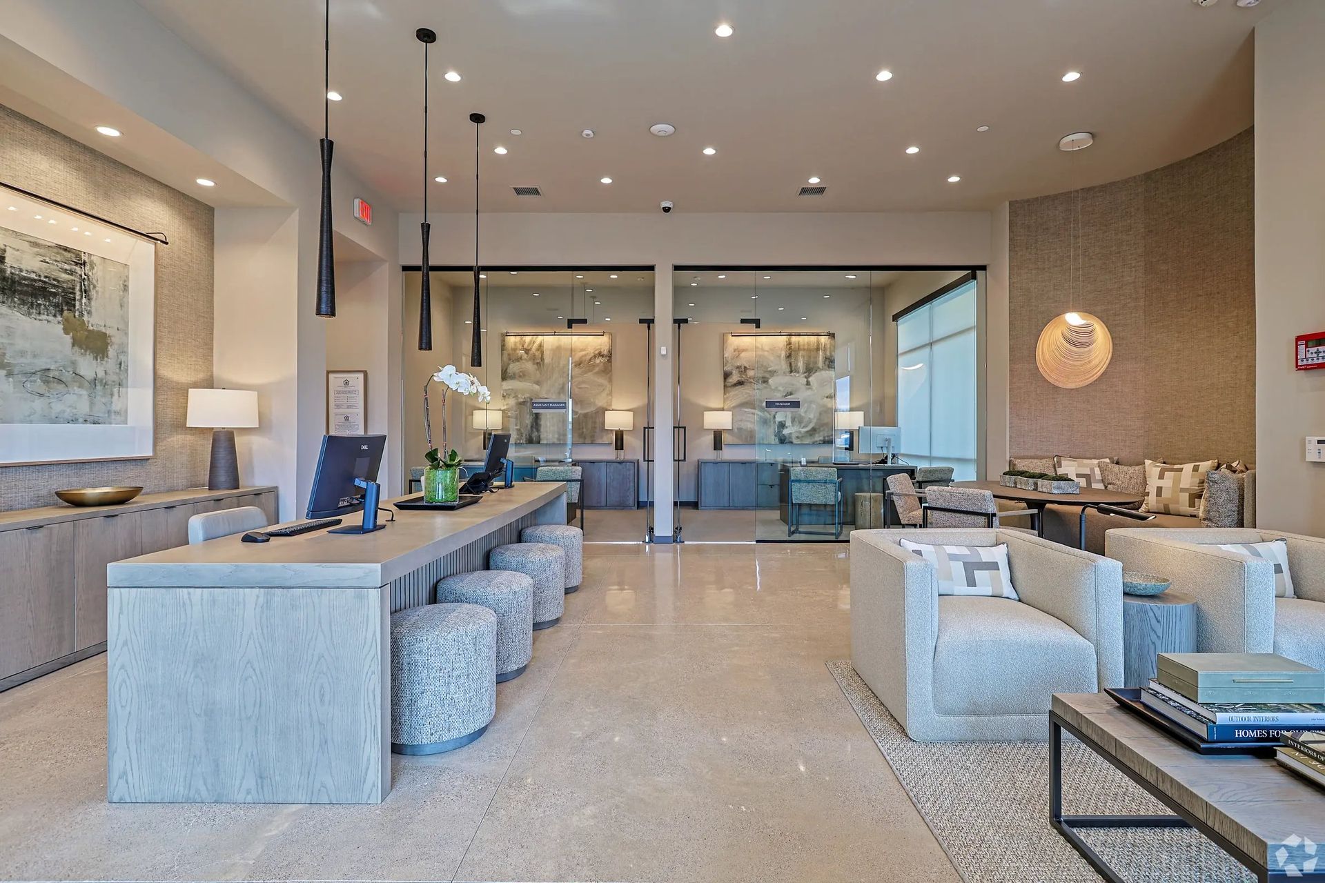Modern hotel lobby with beige sofas, armchairs, tables, and a glossy floor, lit by recessed ceiling lights
