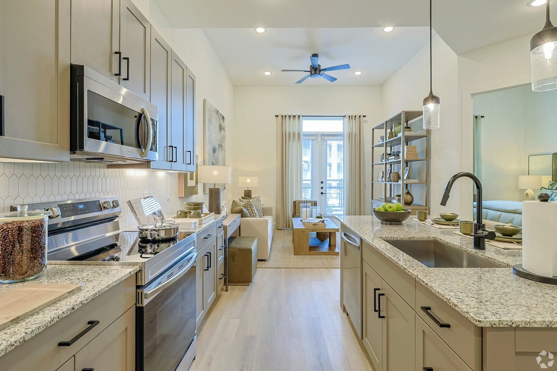 Bright modern galley kitchen with white cabinets, stainless appliances, granite counters, and a windowed dining nook.