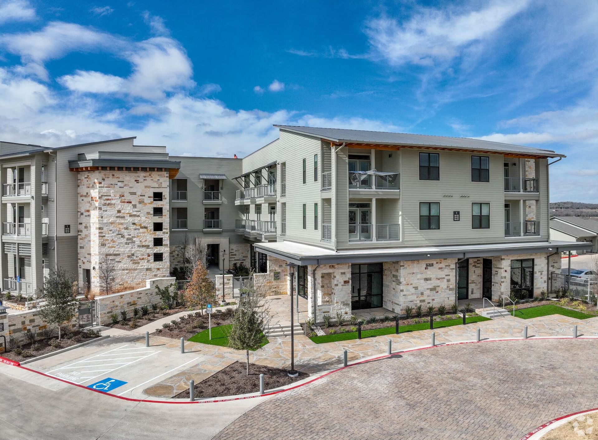 Modern apartment complex exterior with stone accents and a blue sky
