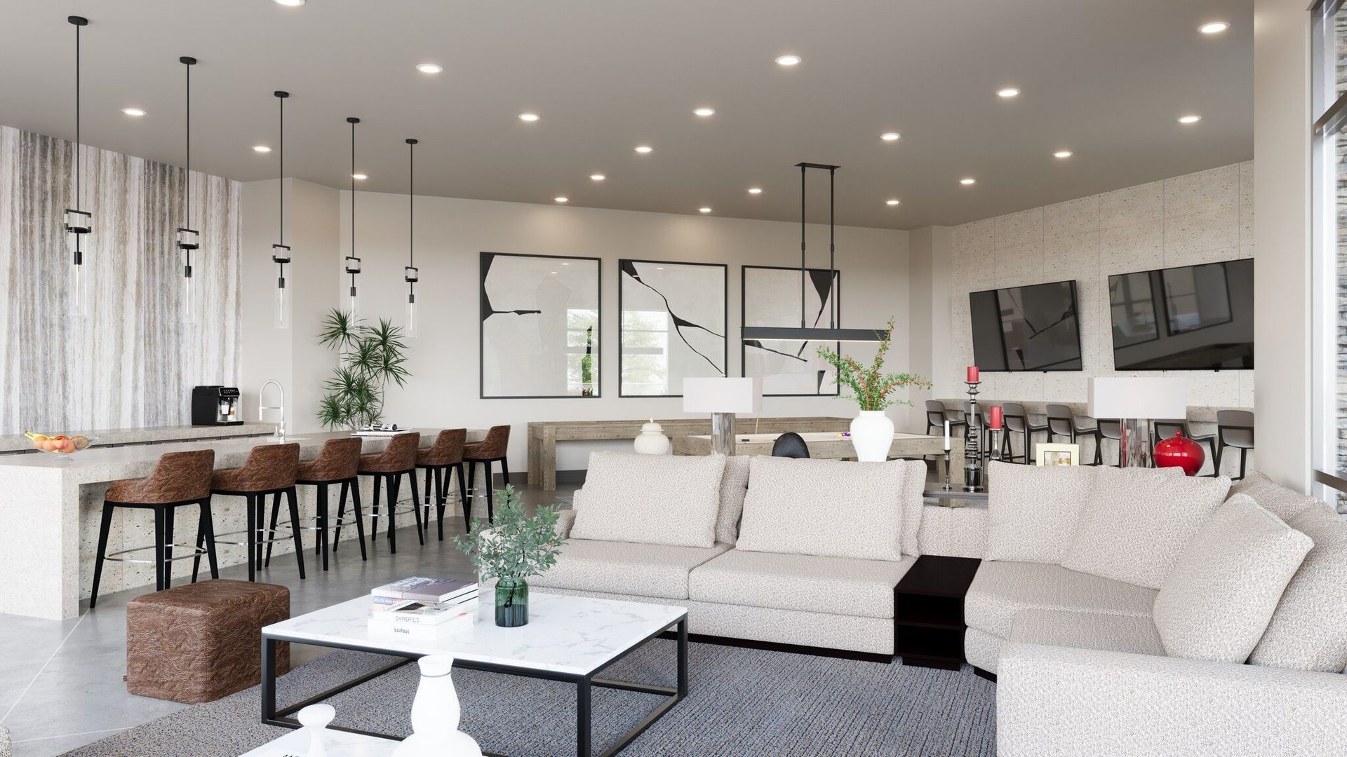 Bright modern living room with white sofa, coffee table, bar seating, and large windows