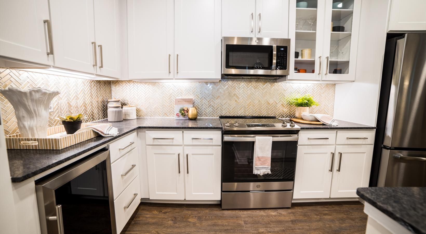 Bright modern white kitchen with stainless steel appliances and wood floor