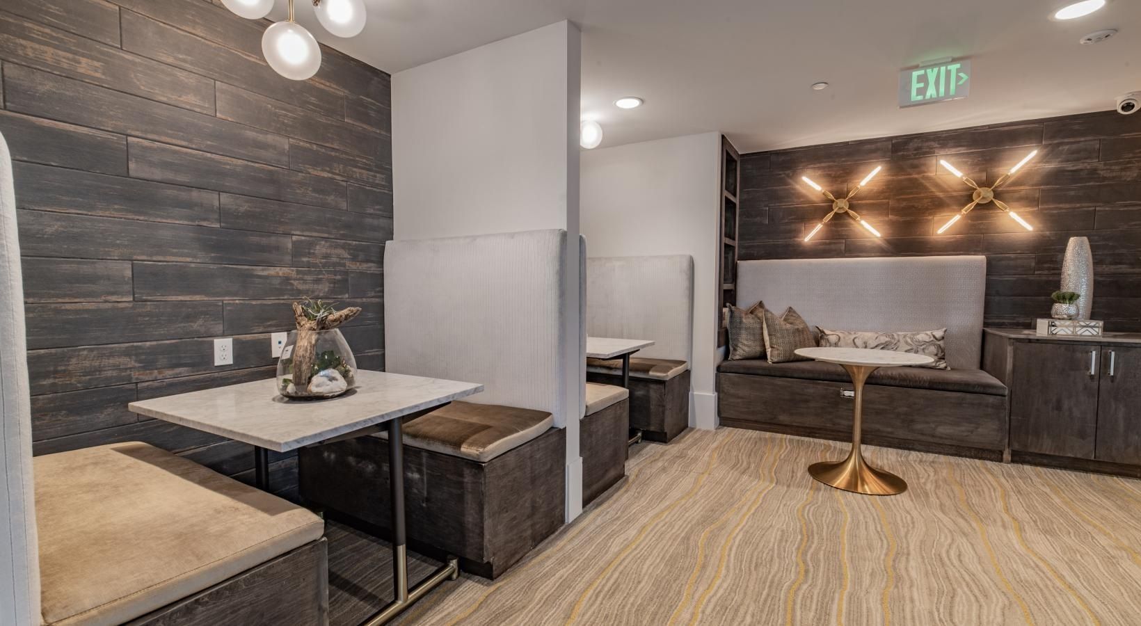 Modern lounge area with marble tables, dark wood walls, bench seating, and a small pedestal table