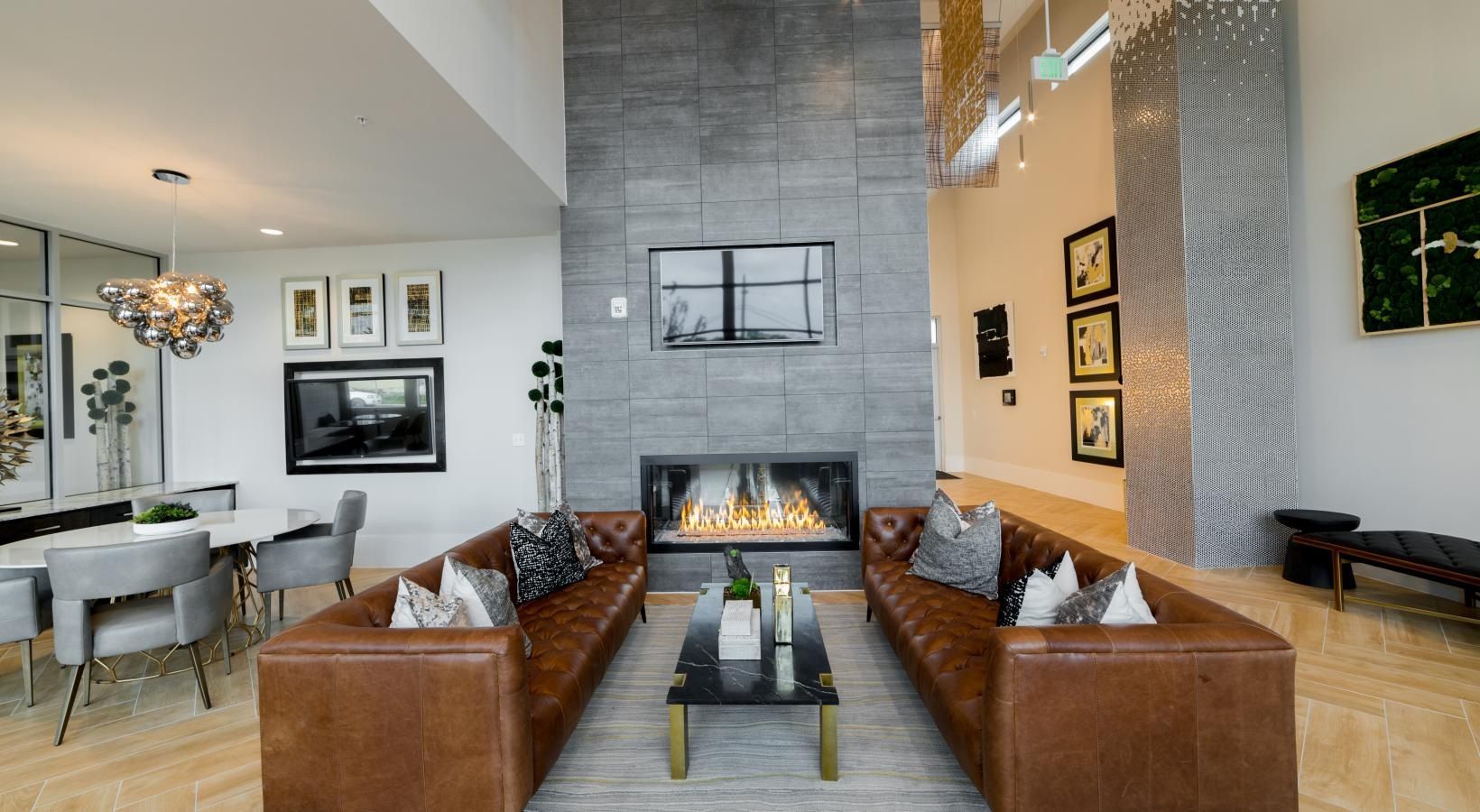 Modern living room with two leather sofas facing a fireplace and tall stone wall