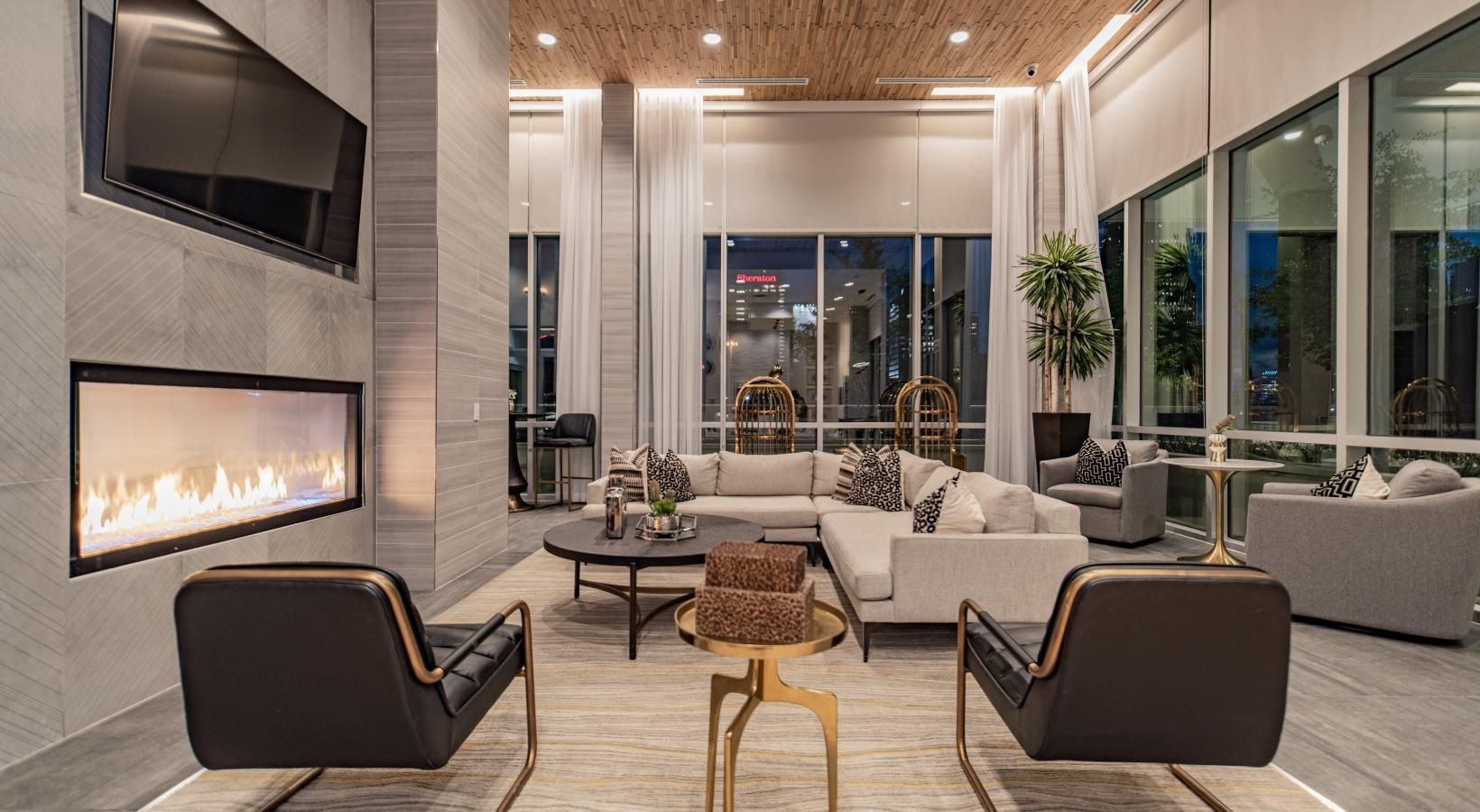 Modern luxury living room with fireplace, large windows, and city night view