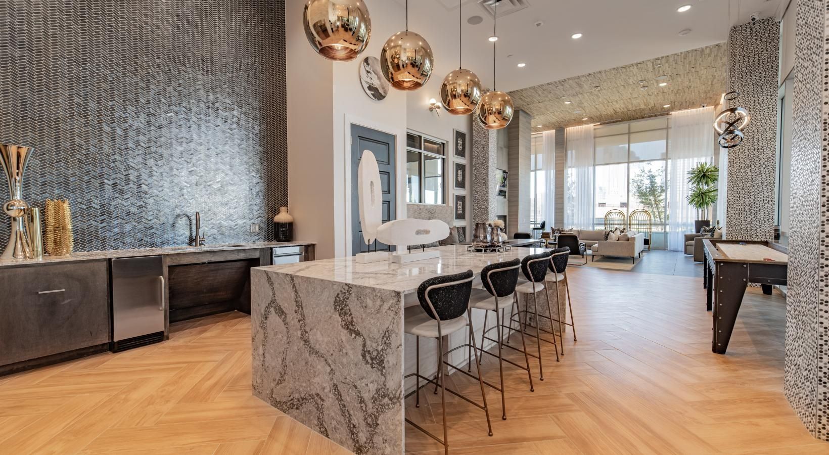 Modern open-concept living room with marble island, bar stools, mirrored wall, and pendant lights