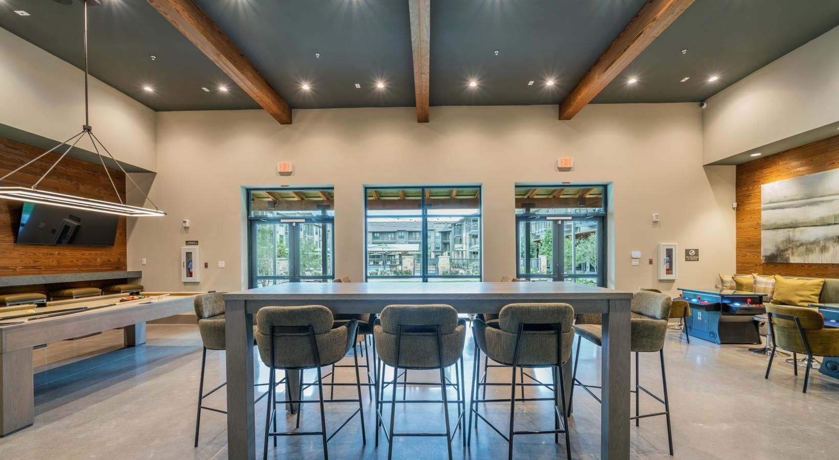 Modern kitchen with a large island, bar stools, pendant lights, and windows overlooking greenery.
