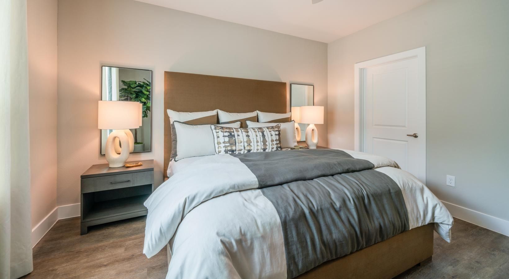 Modern bedroom with a neatly made bed, bedside lamps, and soft neutral decor