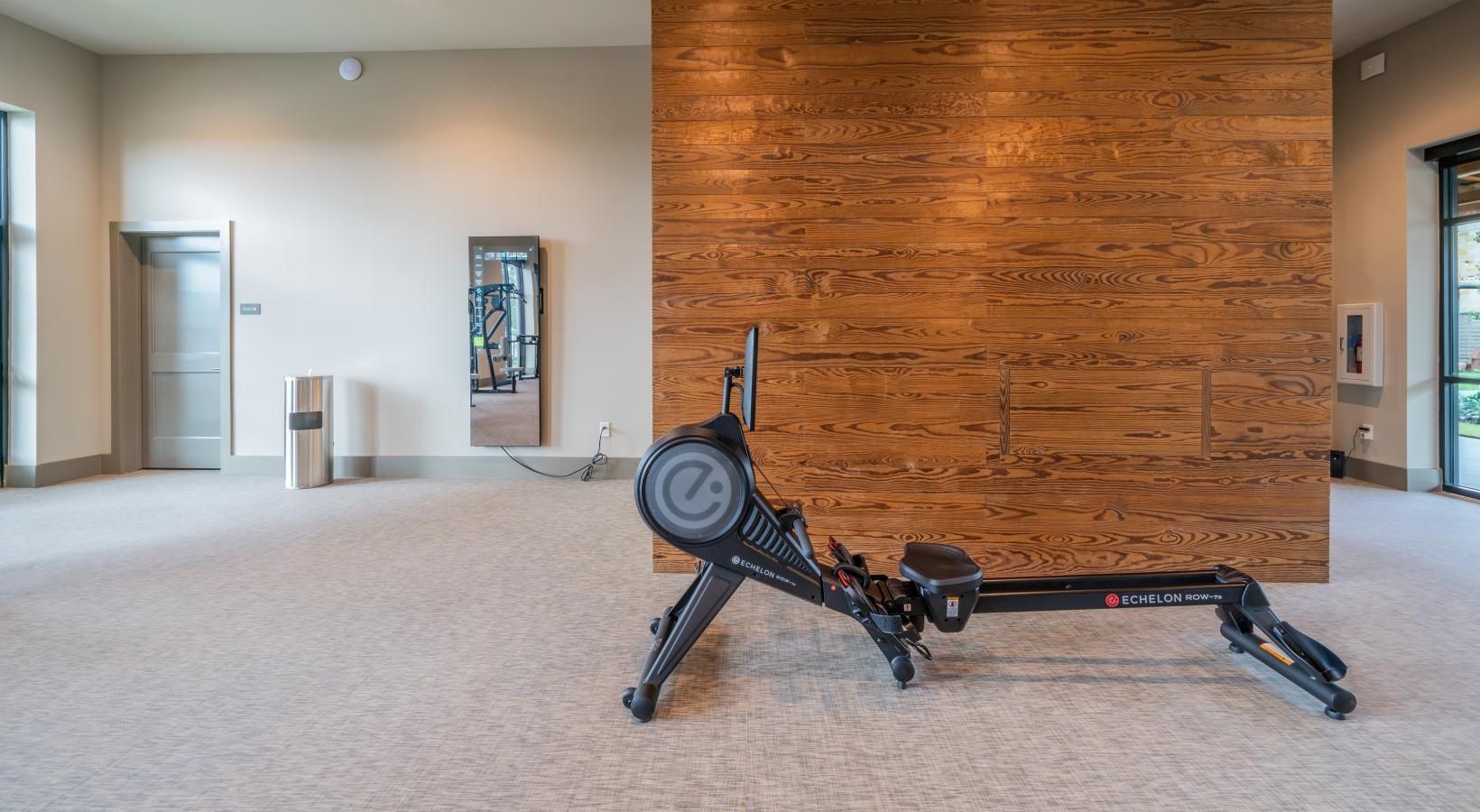 An indoor lobby with a large black exercise machine beside a wood-paneled wall.