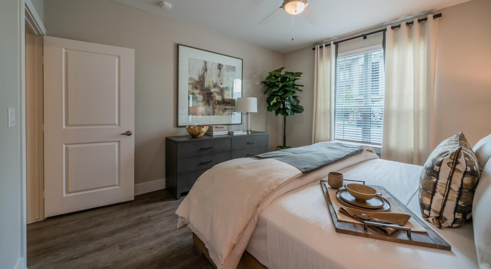 Bright bedroom with a bed, dresser, window, and soft neutral decor