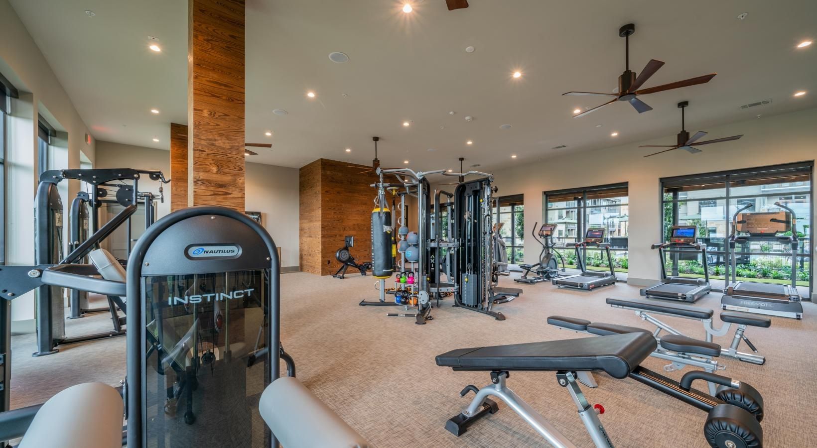Modern gym interior with weight machines, benches, and large windows