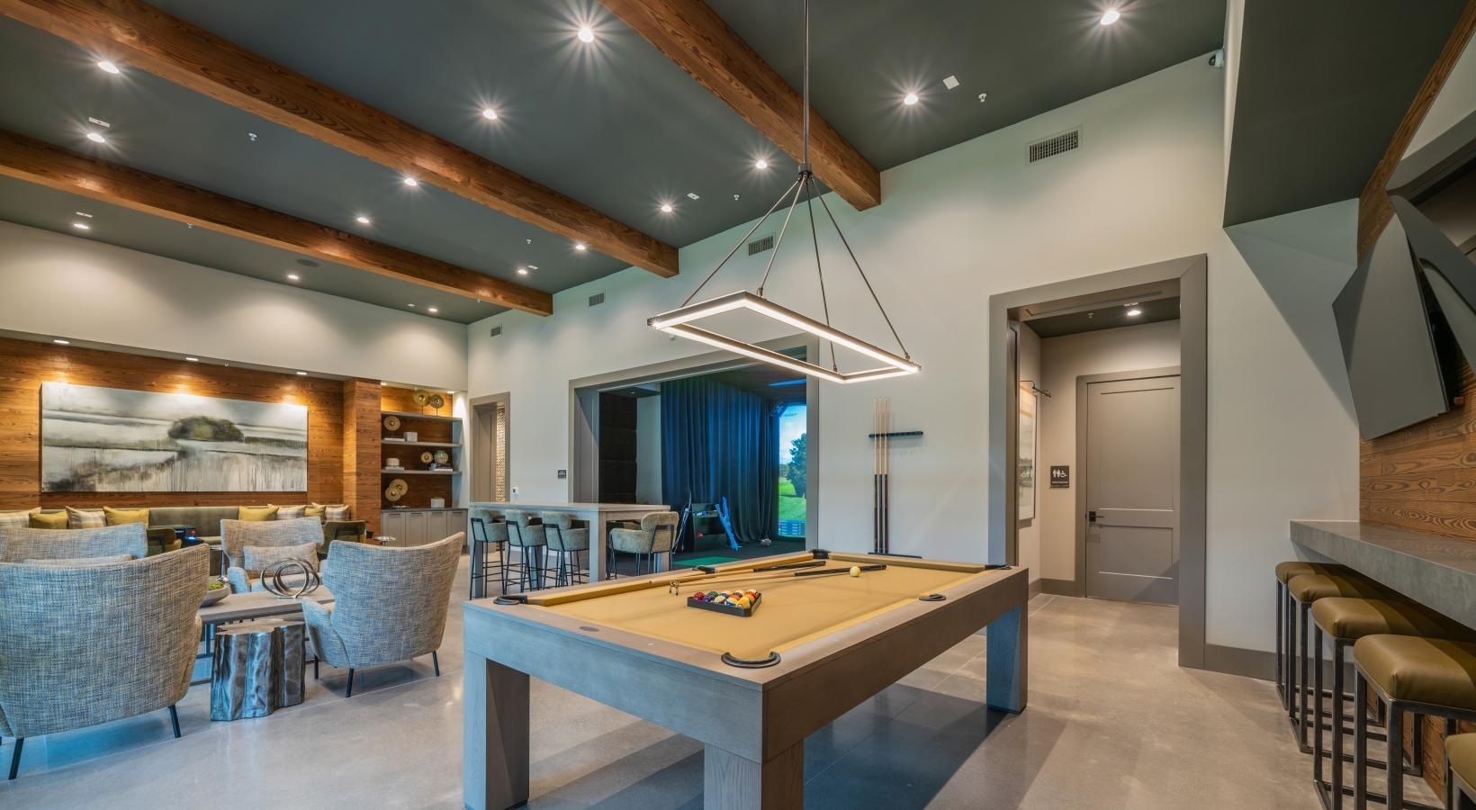 Modern kitchen and living area with pool table, island seating, and exposed wood beams