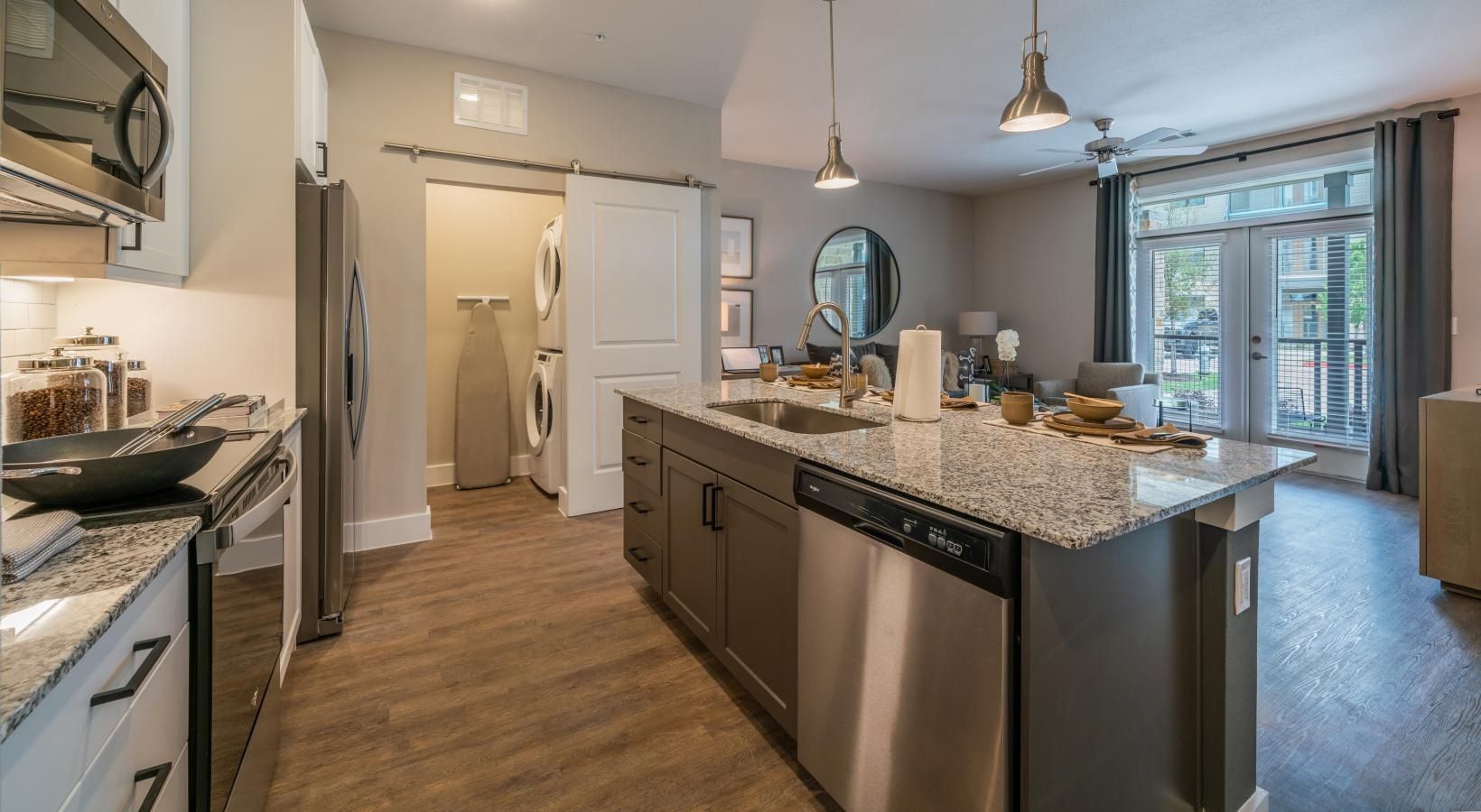Modern kitchen with granite island, stainless appliances, pendant lights, and sliding glass doors to a patio